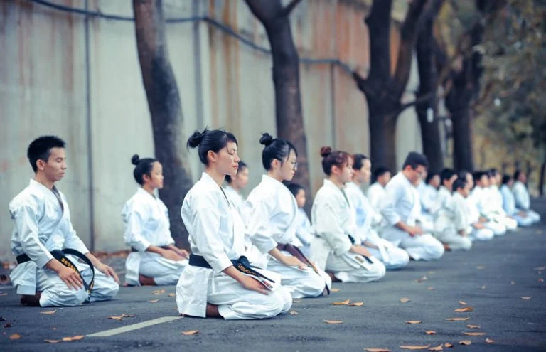 People in white martial arts dresses sitting in meditation.