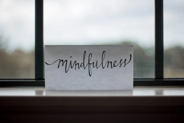 Piece of paper in front of a window with word mindfulness written on it.