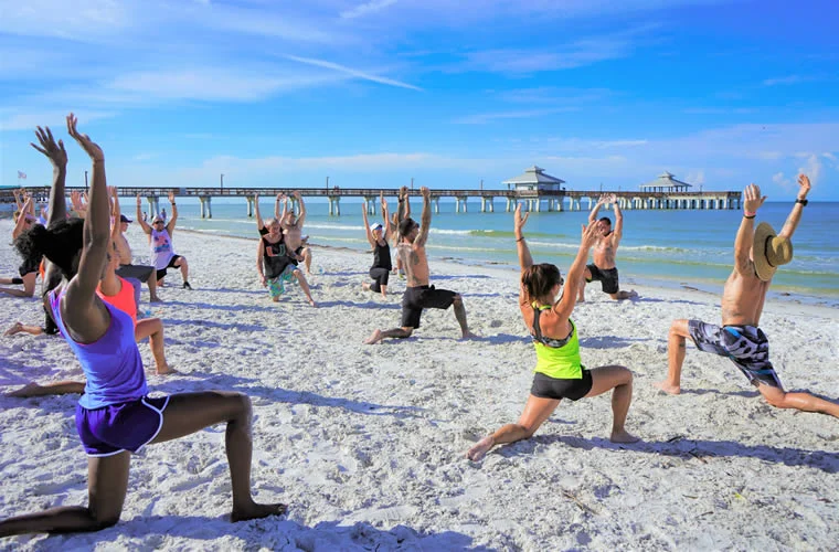 a group of people on a beach doing yoga