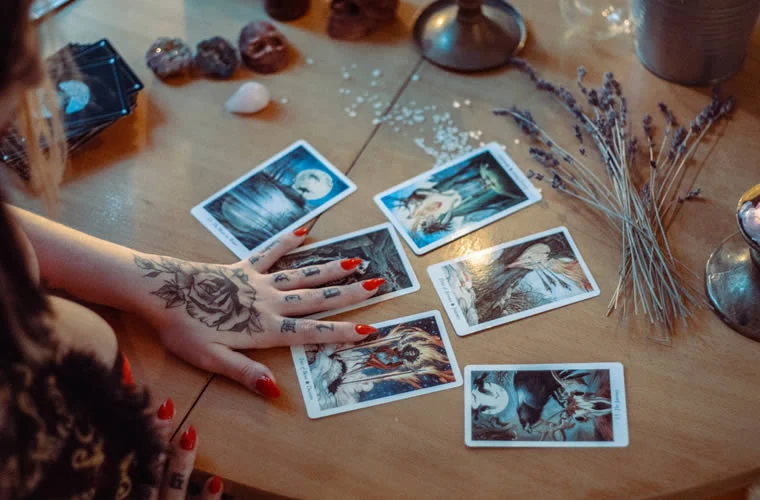 a person's hand with tattoos over open psychic reading cards