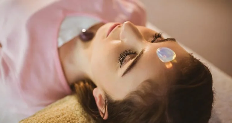 a woman lying down with a crystal on her forehead