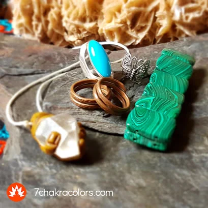 a group of chakra jewelry and crystals on a rock