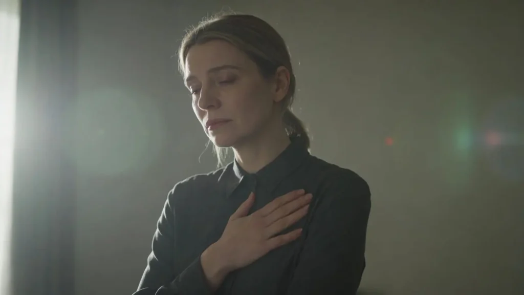 woman standing still with hand over her chest